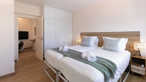 A double bed with two pillows, a bedside table with a lamp, and a wardrobe. - Atlântico Azul - Apartment E (Lagos)