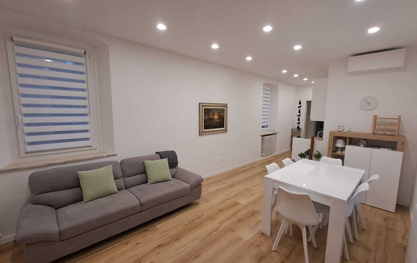 A modern living room with a sofa, dining table, and chairs.
