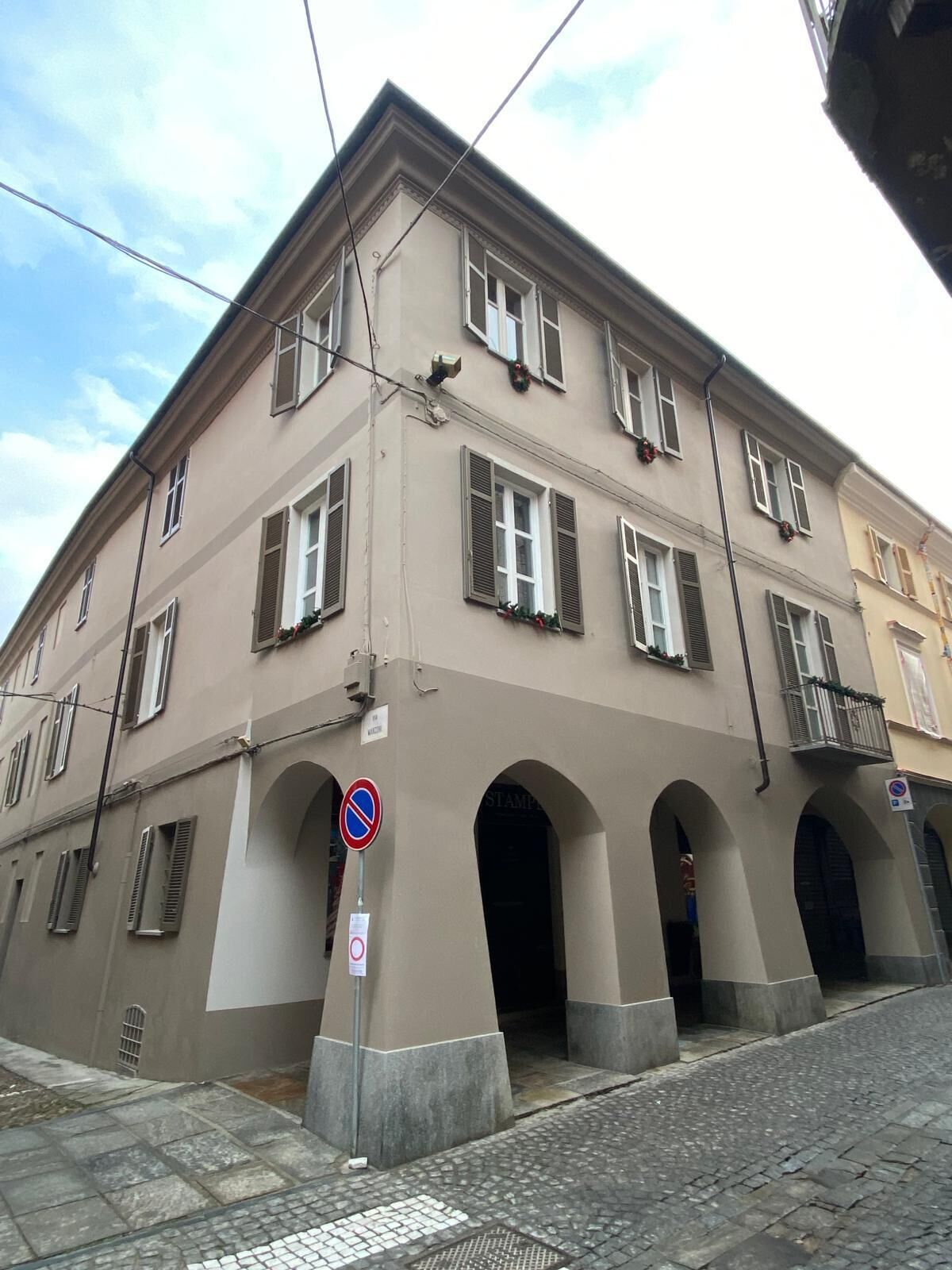 A multi-story building with arched entrances, a no parking sign, and a visible storefront.