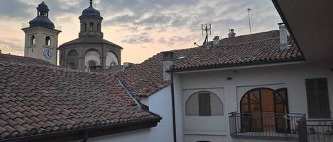 Un edificio con una torre de reloj y una campana, rodeado de otros edificios con tejados de tejas.