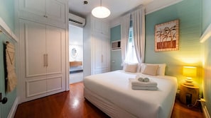 A bedroom with a large bed, a bedside table with a lamp, a wardrobe, and a painting on the wall. - West End Oasis with Pool and Entertaining (West End)
