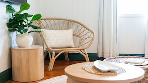 A wicker chair with a cushion, a potted plant, a round wooden side table, and a woven placemat on a round table. - West End Oasis with Pool and Entertaining (West End)