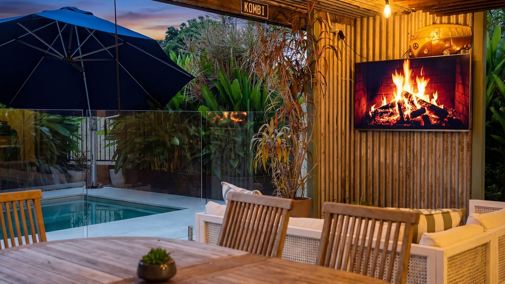 An outdoor seating area with a pool, a fire feature, and a large umbrella.