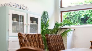 A room with a cabinet containing glassware, a large potted plant, and a wicker chair. - West End Oasis with Pool and Entertaining (West End)