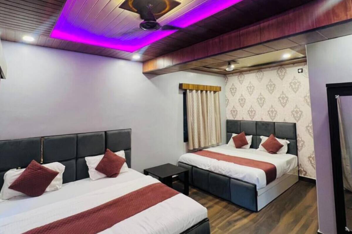 A hotel room with two beds, a ceiling fan, and a patterned wallpaper.