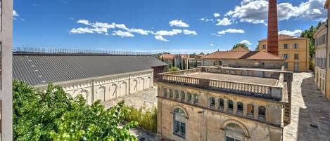 A courtyard with historic buildings, a tall chimney, and a clear blue sky.