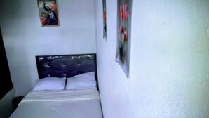Een slaapkamer met een bed, een aan de muur hangend schilderij en een lijst met een foto.