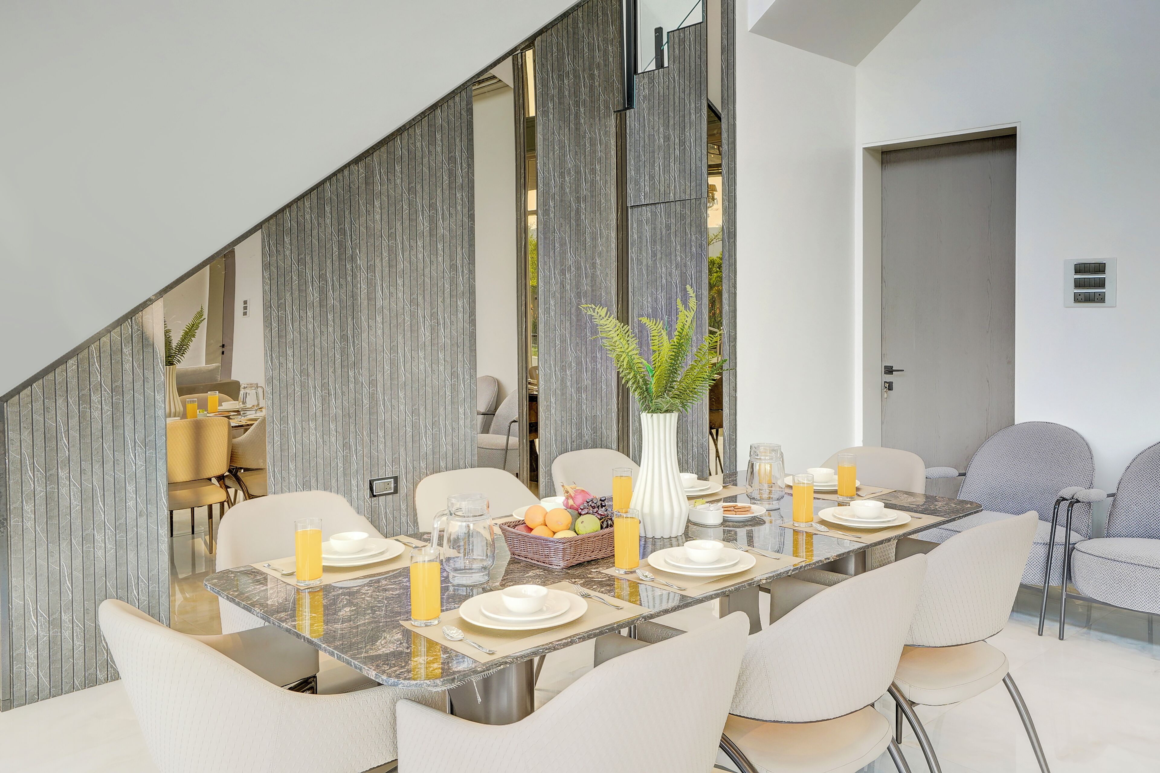 Un comedor moderno con una mesa larga, sillas y un jarrón con flores.