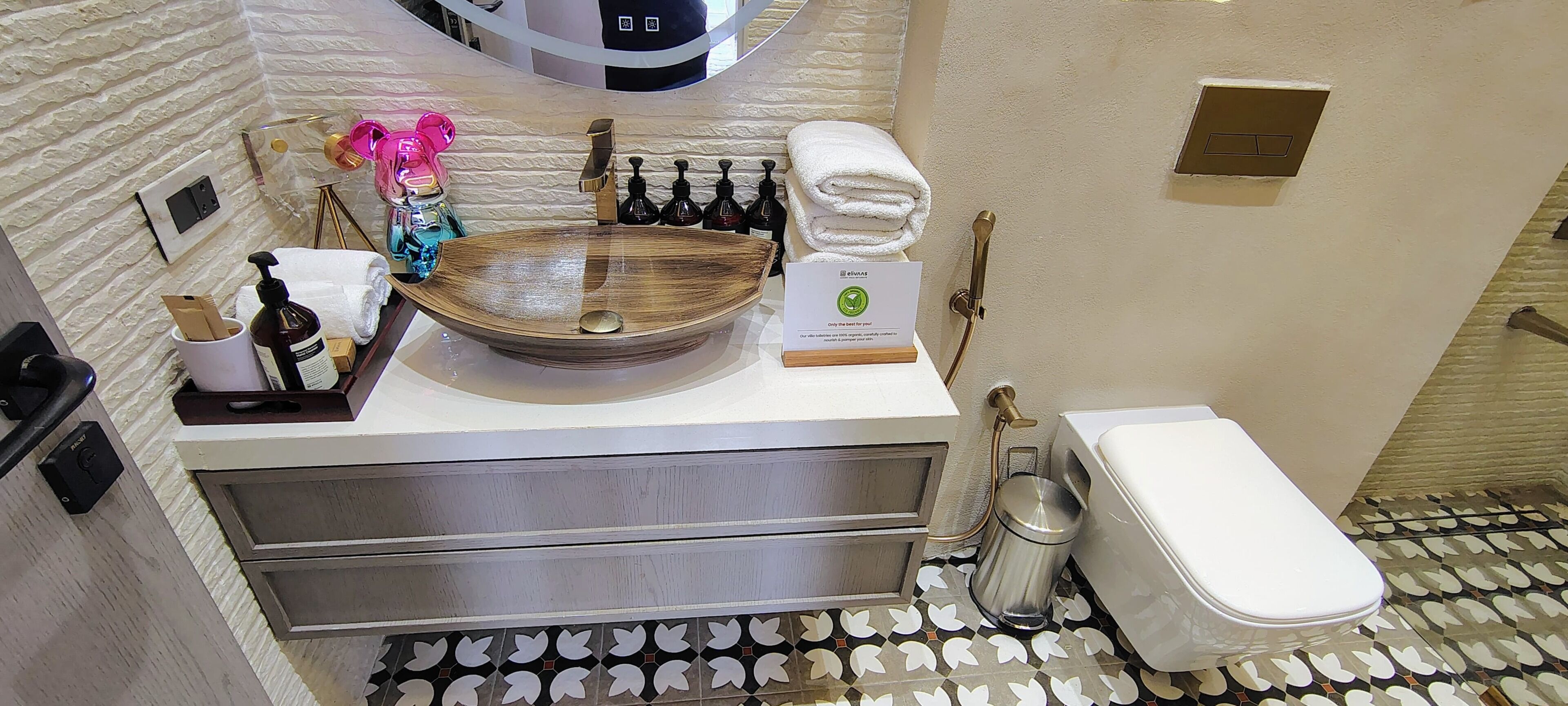 A bathroom with a wooden sink, a white toilet, and patterned floor tiles.