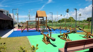 Um parquinho com uma estrutura de escalada, balanços e um escorregador.