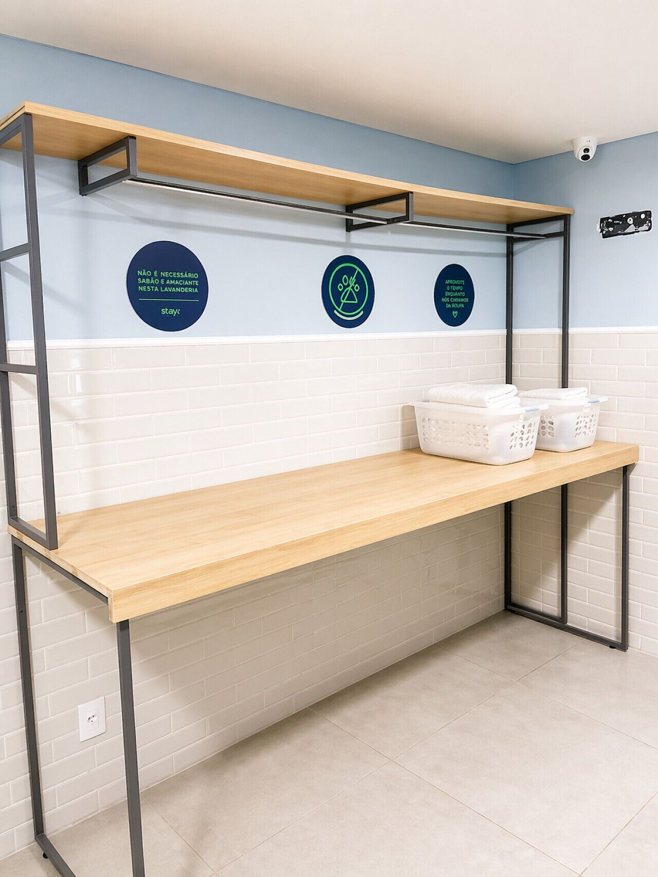 A bathroom with a wooden vanity, white tiled walls, and three circular signs with text and symbols.