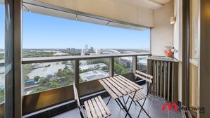 Un balcone con vista sulla città, una panca di legno e un tavolino con un vaso.