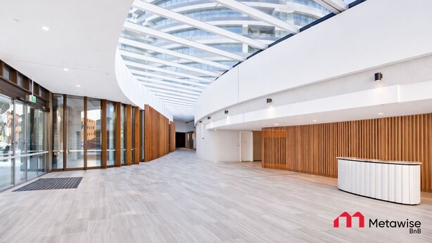 Un edificio moderno con soffitto in vetro curvo, pannelli in legno e una reception.