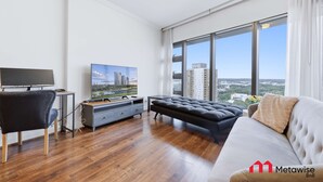 Un soggiorno moderno con un divano, una TV e vista sulla città.