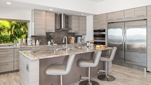 Una cocina moderna con una isla central, electrodomésticos de acero inoxidable y vistas al exterior.