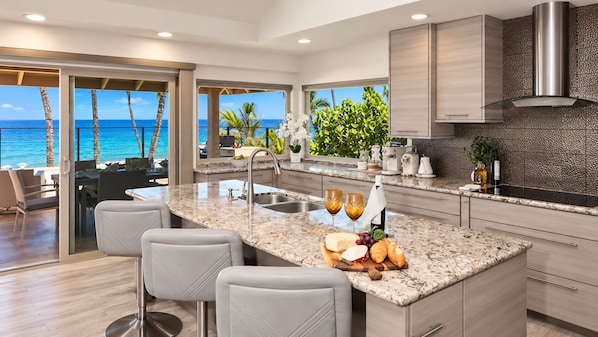 Una cocina moderna con una isla grande, asientos de bar y vistas al océano.