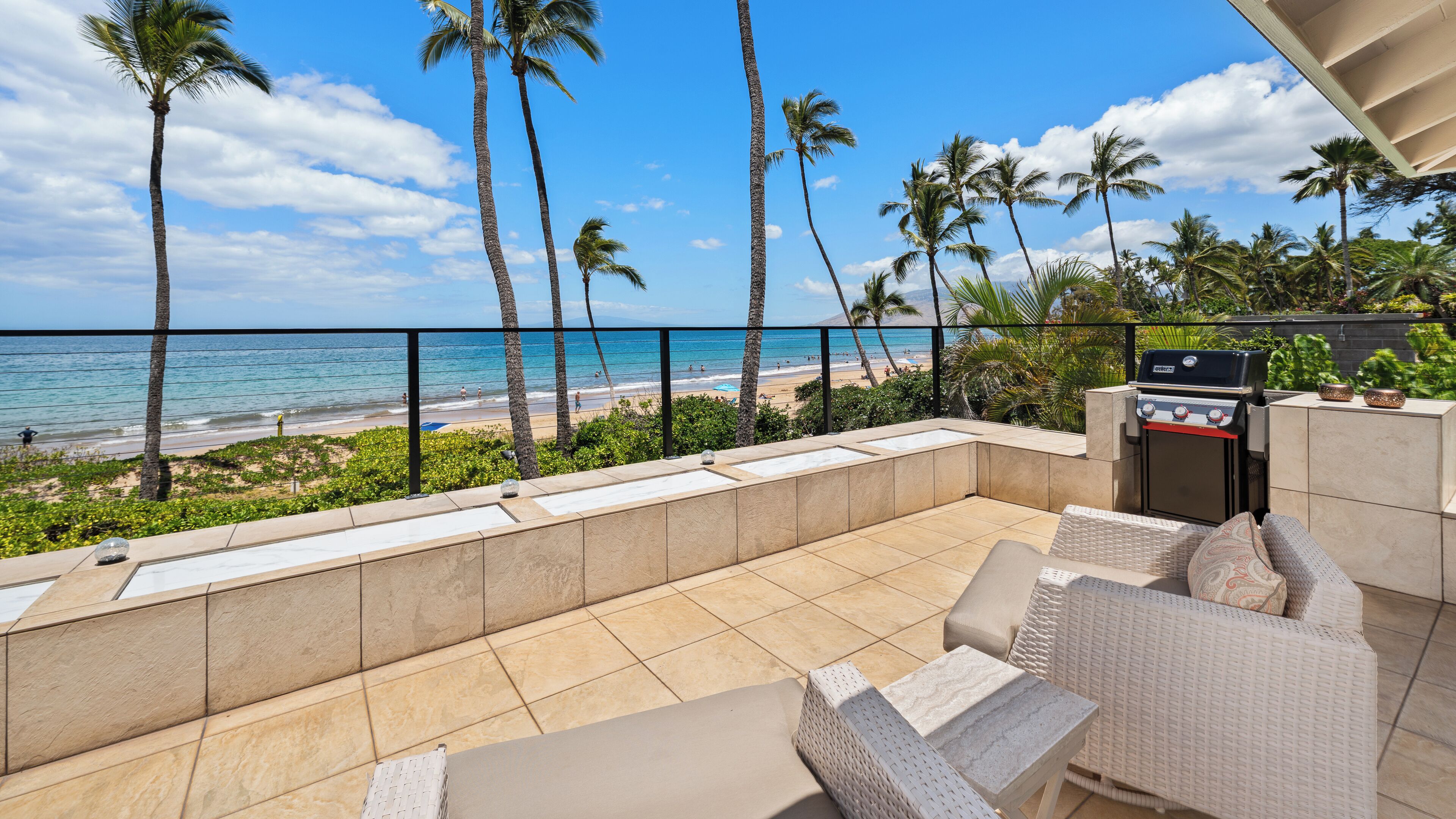 Une terrasse avec mobilier d’extérieur, un barbecue et une vue sur la plage et l’océan.
