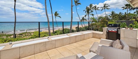 Un patio con mobiliario exterior, una parrilla y vistas a la playa y el océano.