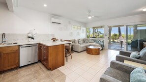 A modern kitchen with a dishwasher, wooden cabinets, and a dining area with a round table and bar stools.
