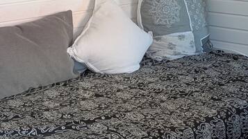 A bed with patterned bedding, two pillows, and heart-shaped wall decorations.