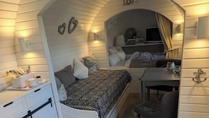 Una habitación pequeña con cama, escritorio y zona de comedor.