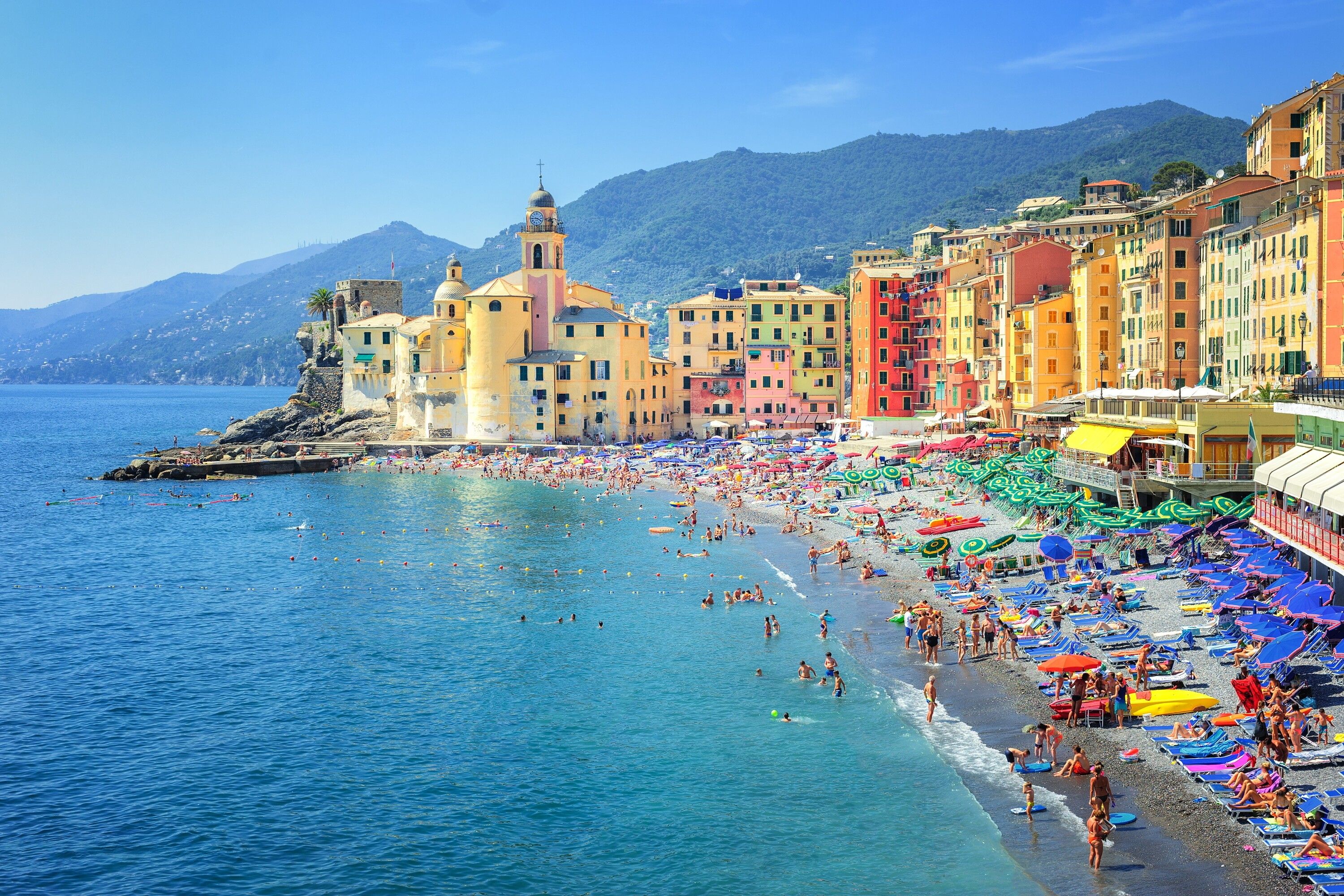 A coastal town with colorful buildings, a beach, and a clear blue sea.