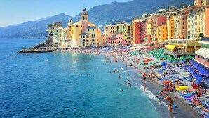 A coastal town with colorful buildings, a beach, and a clear blue sea.