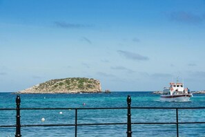 Paisaje costero con un barco y una isla rocosa.