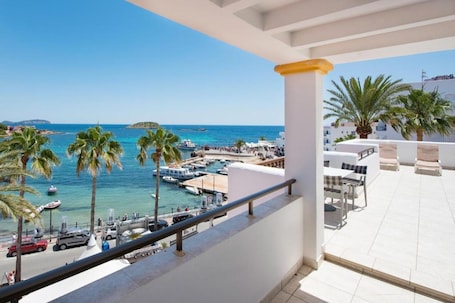 A balcony with a view of a marina, palm trees, and a clear blue sky.
