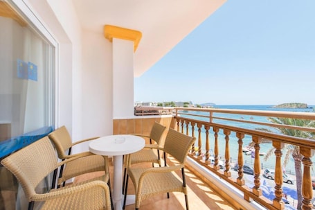 Un balcone con sedie in vimini e un tavolo, con vista su una spiaggia, barche e cielo sereno.. Apartamentos Es canyer