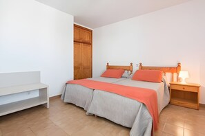 Un dormitorio con cama, mesita de noche, lámpara y un armario de madera.