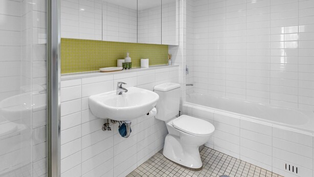 Un bagno con lavandino, water e zona doccia, tutto in bianco.