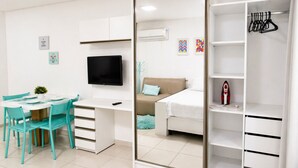 Un dormitorio con cama, escritorio, silla, televisor, armario y armario ropero.