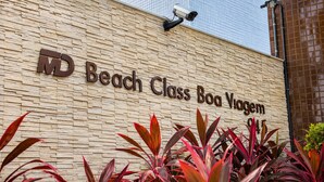 Un edificio con un cartel que dice 'MD Beach Class Boa Viagem' y una cámara de seguridad montada encima del cartel.