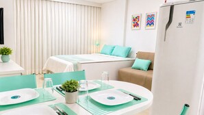 Habitación de hotel con una cama, una mesa de comedor y vajilla, cubiertos y una planta pequeña.