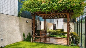 Eine hölzerne Pergola mit Kletterpflanzen, einer Bank und einem gepflegten Garten.