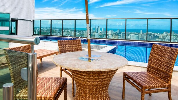 A rooftop terrace with a pool, wicker furniture, and a city view. - Beach Class Ilha do Leite- Flat/Studio 1105 (Ilha do Leite)