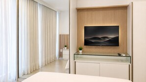 A modern hotel room with a large bed, a glass console table, a mounted TV, and a view of the hallway. - Beach Class Ilha do Leite- Flat/Studio 1105 (Ilha do Leite)