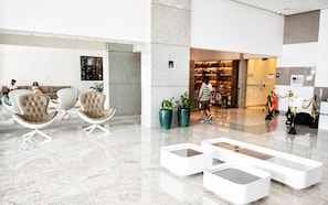 A modern lobby with seating areas, a reception desk, and a view of the city at night. - Beach Class Ilha do Leite- Flat/Studio 1105 (Ilha do Leite)