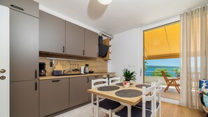 Eine kleine Küche mit modernen Geräten, ein Essbereich mit Tisch und Stühlen sowie ein Balkon mit Blick.