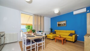 Ein modernes Wohnzimmer mit Essbereich, einem gelben Sofa und Blick ins Freie.
