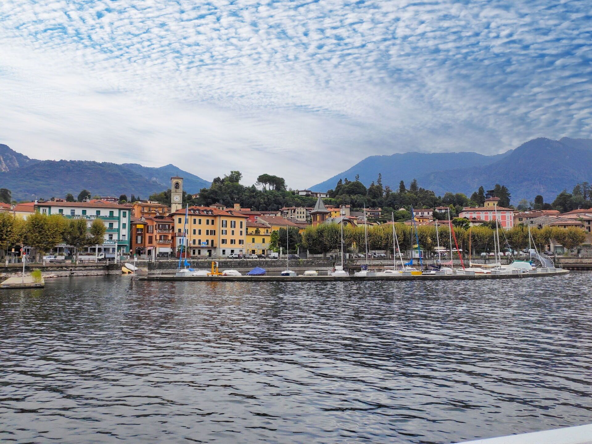 Una cittadina sul lungofiume con edifici colorati, una torre dell'orologio e barche ormeggiate lungo il fiume.