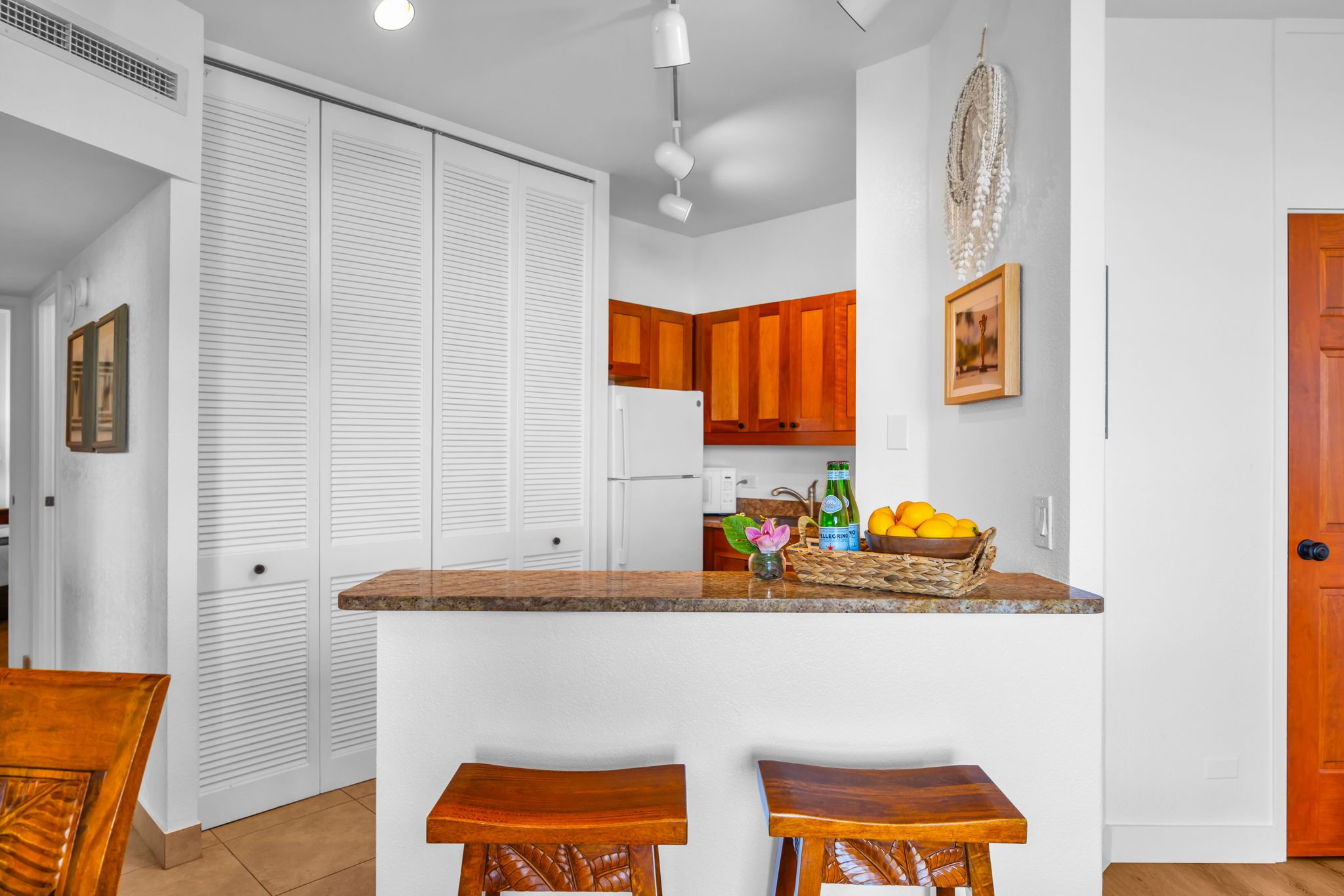 A kitchen with white cabinets, a wooden countertop, and two stools.