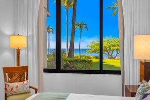 Ein Hotelzimmer mit großem Fenster, einem Bett, einem Sessel und einer Lampe.