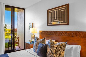 Quarto de hotel com cama, mesa de cabeceira, luminária, quadro e vista para o exterior.