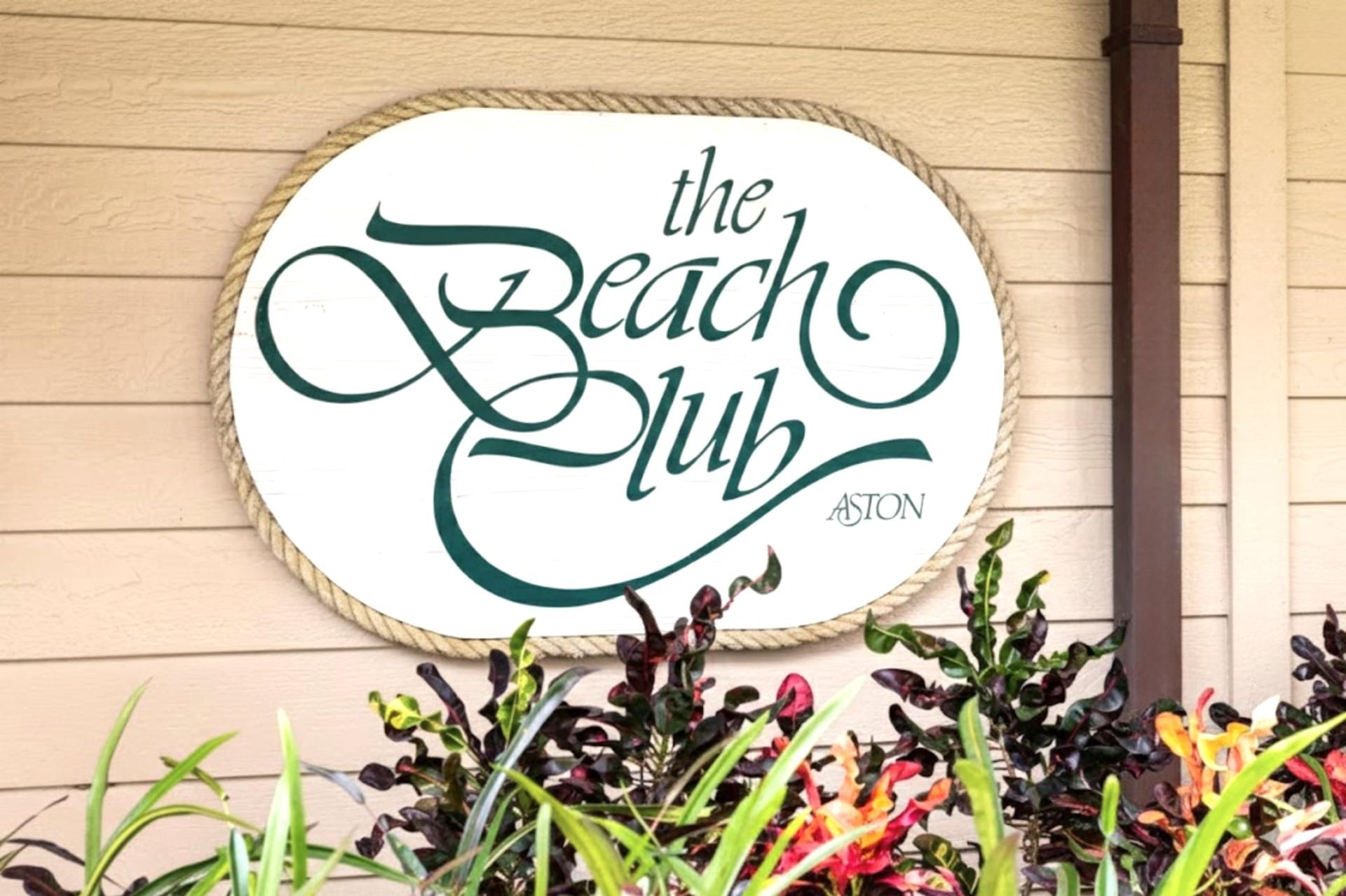 A sign with the text "the Beach Club" on a wooden wall.