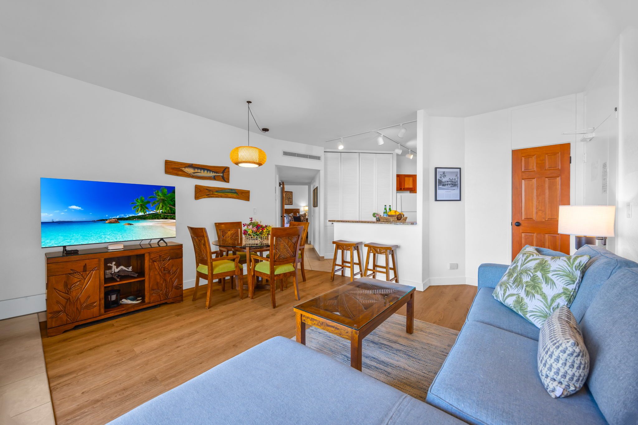 Una sala de estar con televisor, muebles de madera, un sofá y una zona de comedor.