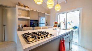 A modern kitchen with a gas stove, white cabinets, and pendant lights. - NEW 2BR Escape | Plunge Pool & BBQ | Near Beaches (Noord)