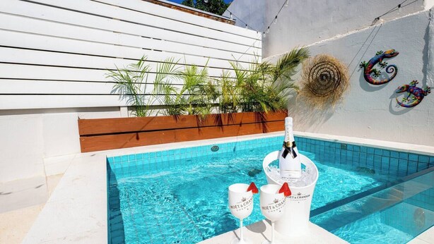 A swimming pool with a champagne bottle and glasses, surrounded by plants and a decorative wall. - NEW 2BR Escape | Plunge Pool & BBQ | Near Beaches (Noord)