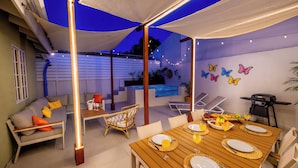 An outdoor patio with a dining table set for four, surrounded by chairs, a sofa, and a wicker chair. - NEW 2BR Escape | Plunge Pool & BBQ | Near Beaches (Noord)